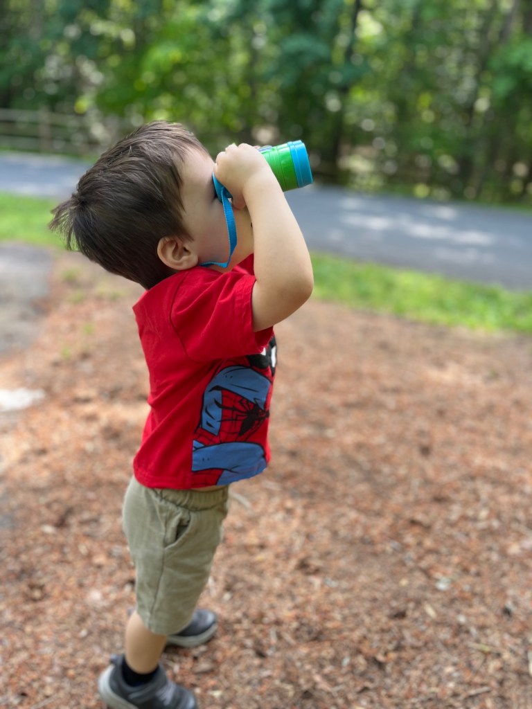 Boy in a red shirt with green toy binoculars.
